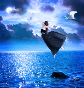 Beautiful girl jumping into the blue night sky
